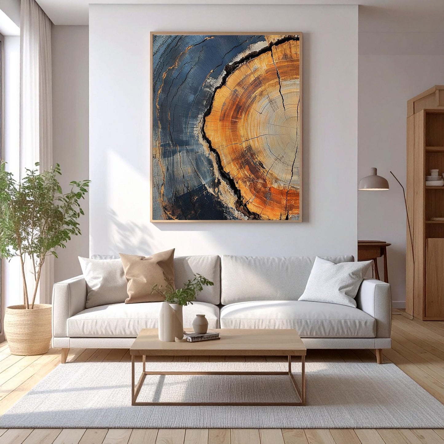 a modern living room with a large abstract painting hanging on the wall above a white sofa. The sofa is positioned in front of a wooden coffee table, which has a vase of flowers on it. The room also features a large window, a wooden floor, and a wooden bookshelf.