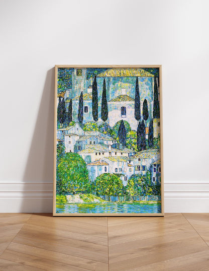The image is a framed painting depicting a picturesque landscape with a village nestled among trees and a body of water in the foreground.