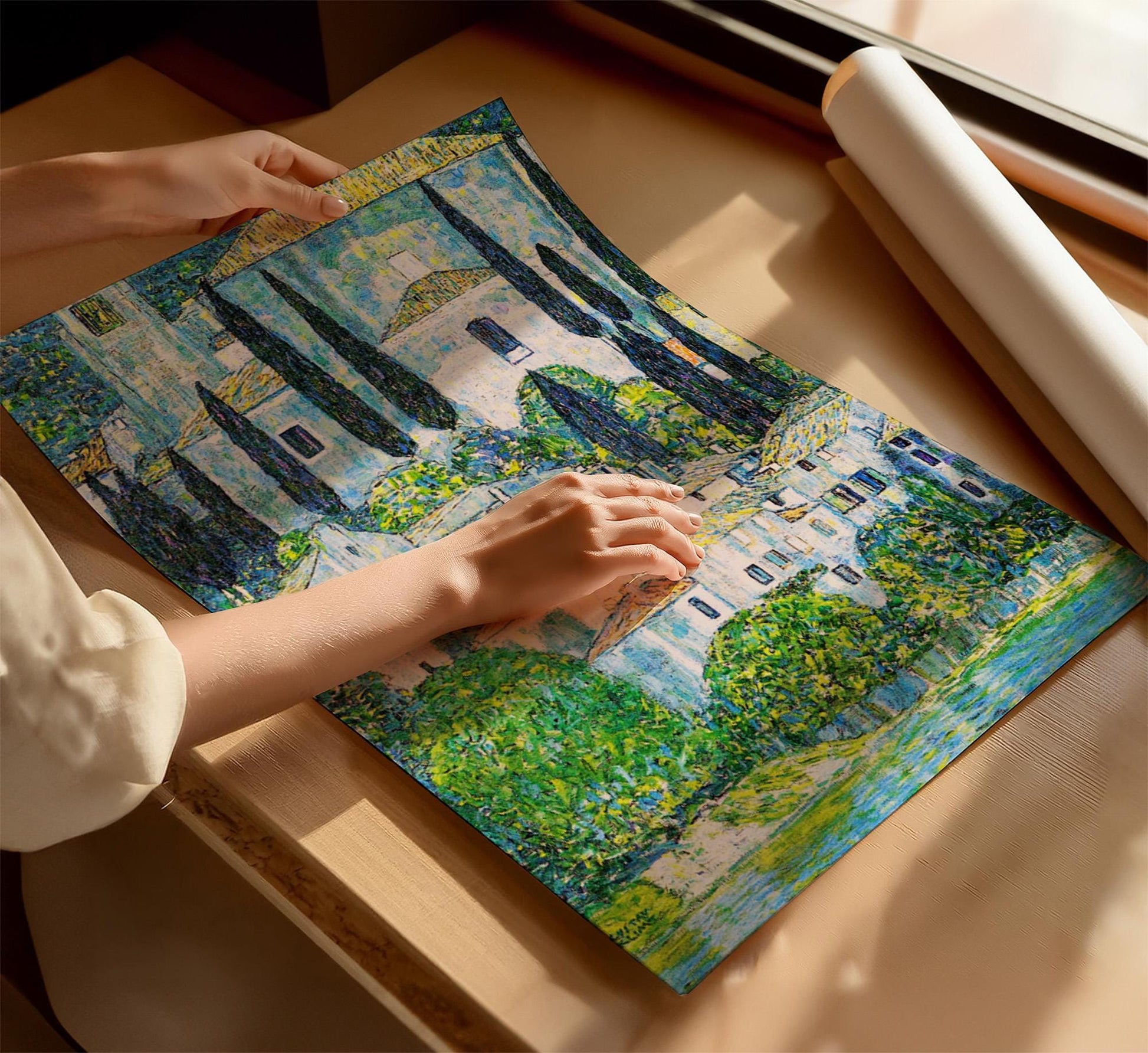 A person&#39;s hands are holding a large, colorful painting depicting a scenic landscape with trees and buildings.